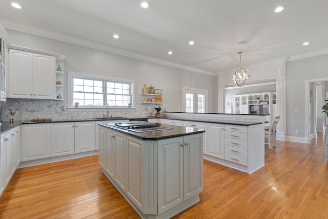 kitchen with open shelves, a peninsula, a sink, and a center island