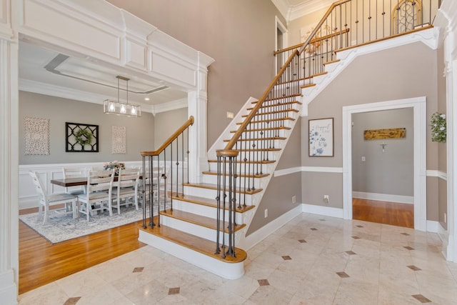 staircase with ornamental molding, a high ceiling, and a notable chandelier