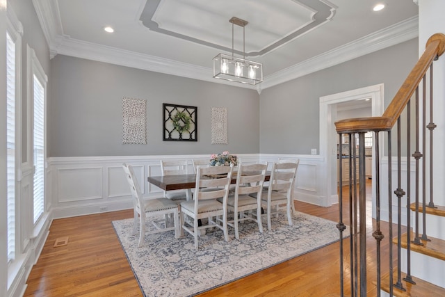 dining space featuring crown molding, stairway, a wainscoted wall, and light wood-style floors