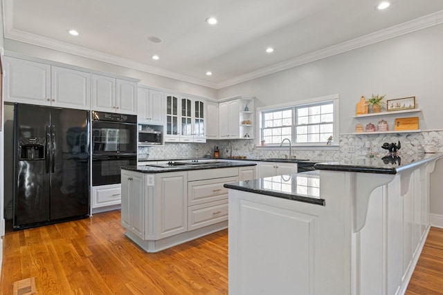 kitchen with a peninsula, black appliances, white cabinetry, open shelves, and a sink