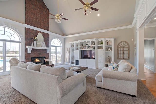 living area featuring a brick fireplace, plenty of natural light, high vaulted ceiling, and crown molding