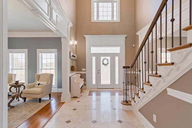 entryway featuring baseboards, stairway, wood finished floors, a high ceiling, and crown molding