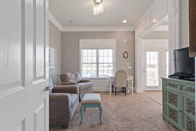 living area featuring a wealth of natural light, carpet, crown molding, and a decorative wall