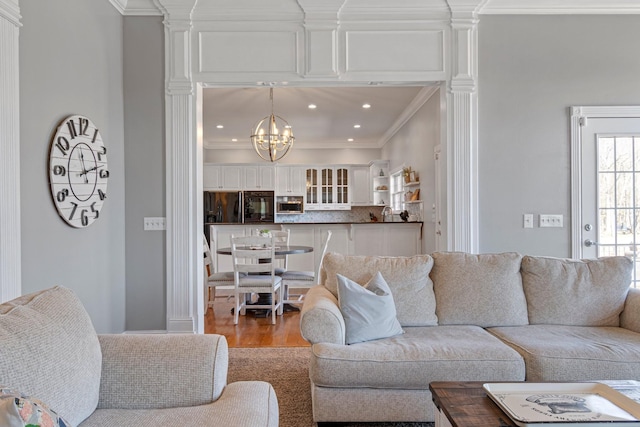 living area featuring light wood-style floors, ornamental molding, a chandelier, and recessed lighting