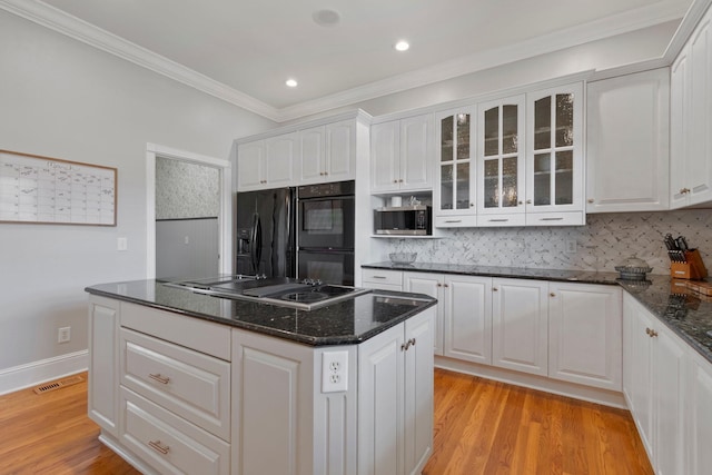 kitchen featuring black appliances, light wood-style flooring, glass insert cabinets, and white cabinetry