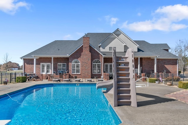 view of swimming pool with a fenced in pool, a patio, fence, a water slide, and french doors