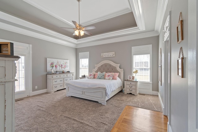 bedroom featuring ornamental molding, a raised ceiling, carpet flooring, and multiple windows