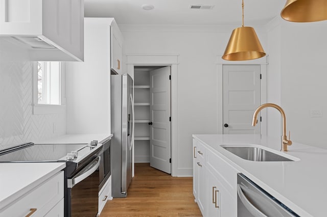 kitchen with stainless steel appliances, light countertops, visible vents, a sink, and light wood-type flooring