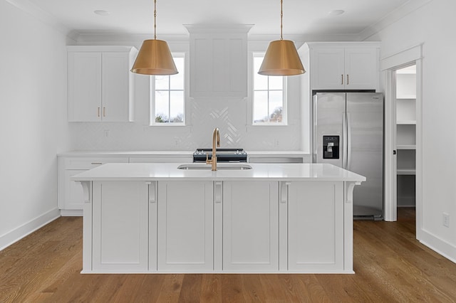 kitchen with a sink, light countertops, stainless steel fridge, and white cabinetry