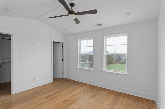 unfurnished bedroom with light wood-style flooring, visible vents, vaulted ceiling, and baseboards