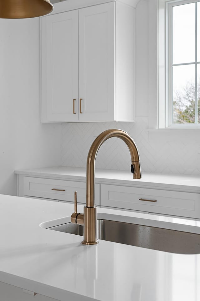 room details with light countertops, white cabinetry, a sink, and decorative backsplash