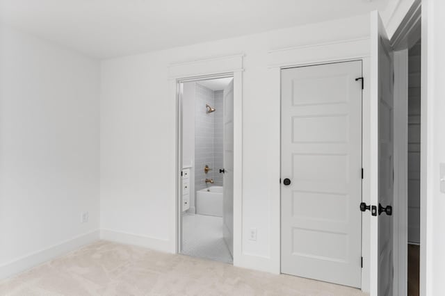 unfurnished bedroom featuring carpet, a closet, connected bathroom, and baseboards