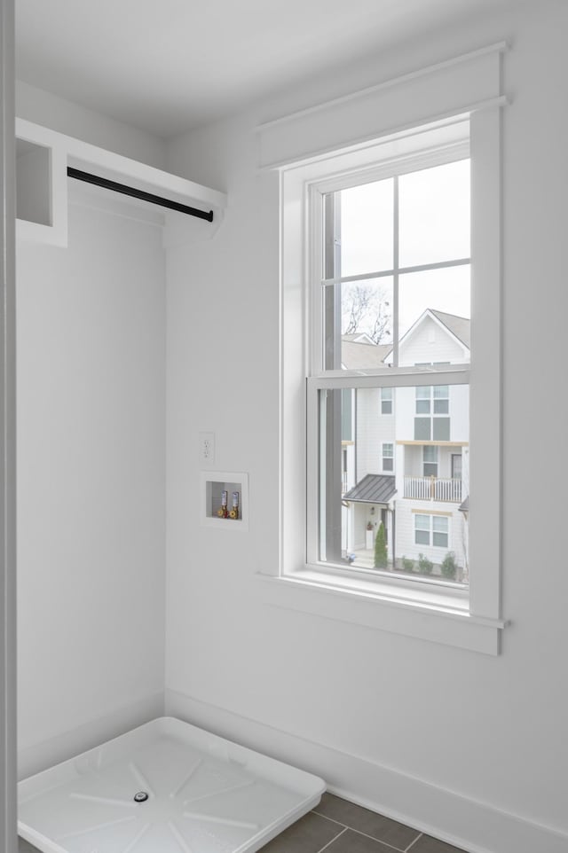 clothes washing area with laundry area, dark tile patterned flooring, washer hookup, and a healthy amount of sunlight