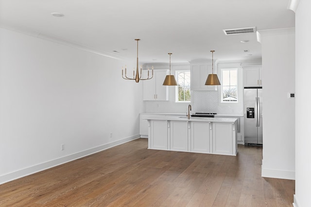 kitchen with stainless steel refrigerator with ice dispenser, light countertops, visible vents, white cabinetry, and wood finished floors