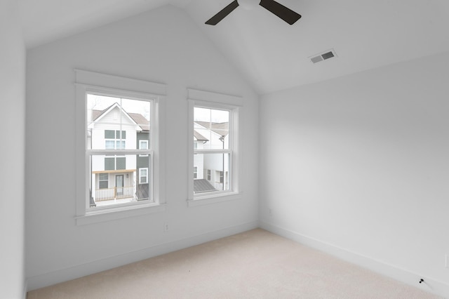 spare room with visible vents, light carpet, vaulted ceiling, ceiling fan, and baseboards