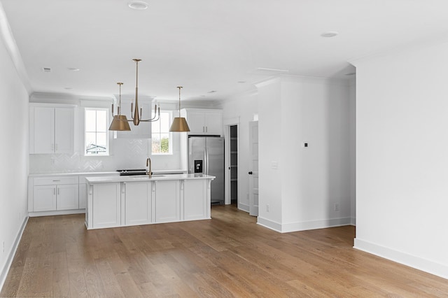 kitchen featuring light wood-style flooring, a sink, light countertops, ornamental molding, and stainless steel fridge with ice dispenser