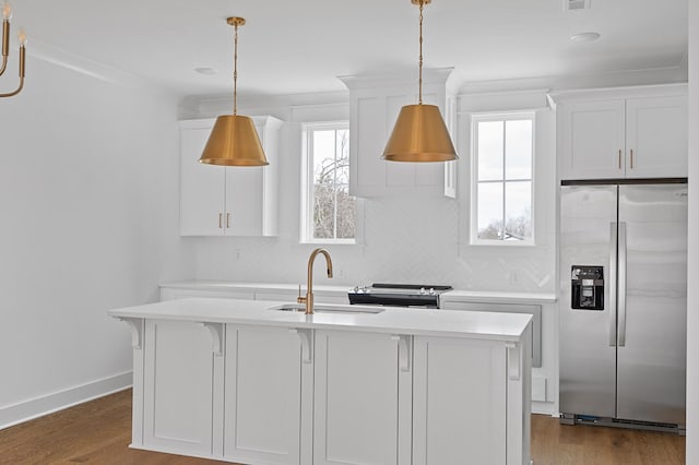 kitchen featuring light countertops, wood finished floors, a sink, and stainless steel fridge with ice dispenser