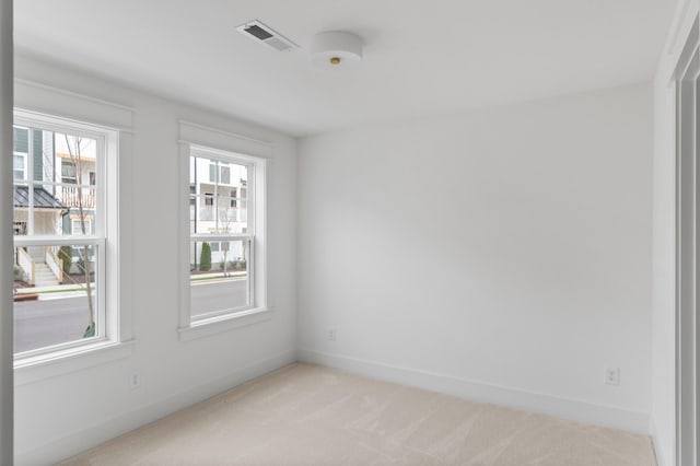 empty room featuring light colored carpet, visible vents, and baseboards