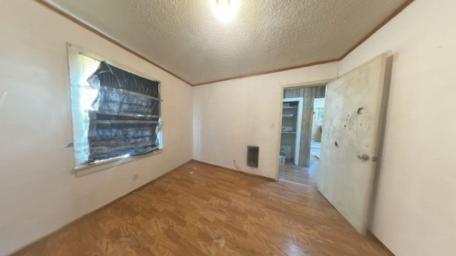 unfurnished room featuring a textured ceiling, wood finished floors, and crown molding