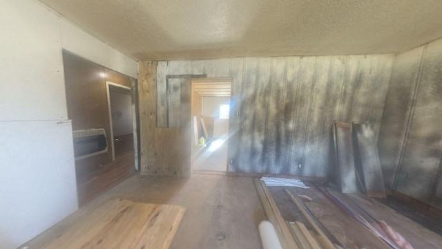 unfurnished room featuring a textured ceiling, heating unit, and wood finished floors