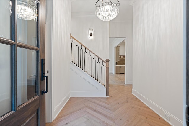 entrance foyer featuring a notable chandelier, stairs, baseboards, and crown molding