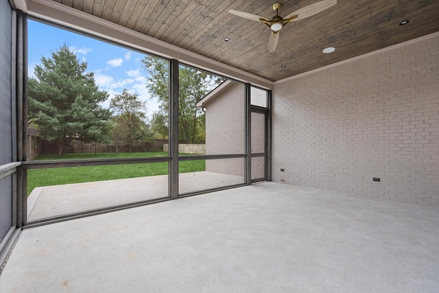 unfurnished sunroom with wood ceiling and a ceiling fan