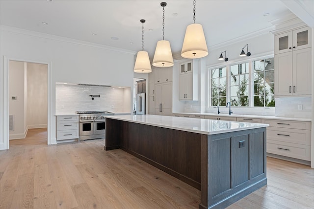 kitchen with visible vents, light wood-style flooring, high quality appliances, light countertops, and crown molding