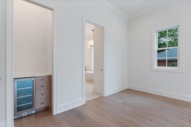 unfurnished bedroom with baseboards, wine cooler, light wood-style flooring, and crown molding