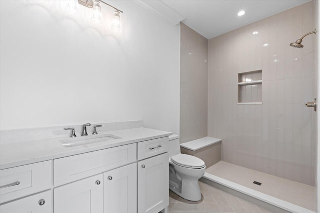 bathroom with tile patterned flooring, tiled shower, vanity, and toilet