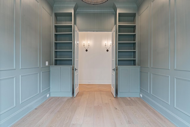 interior space with light wood-type flooring, built in features, and a decorative wall