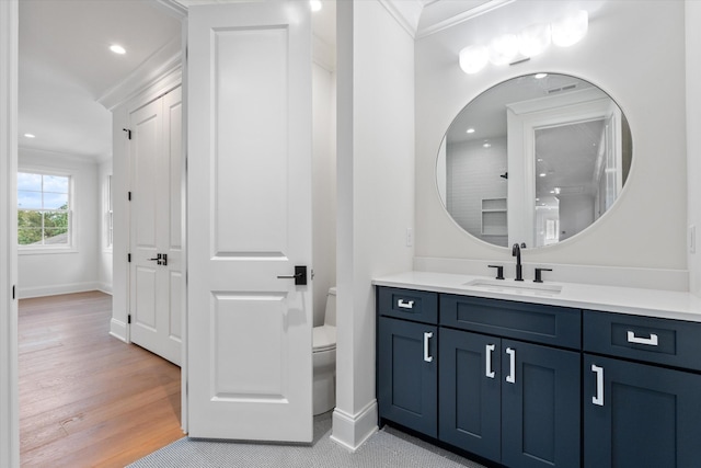 bathroom with toilet, visible vents, vanity, baseboards, and ornamental molding