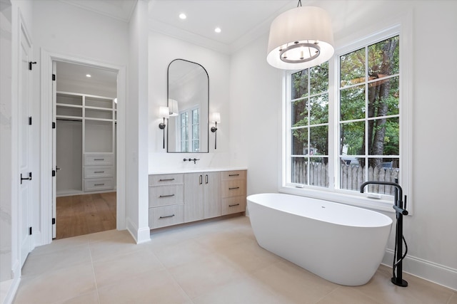 bathroom featuring crown molding, recessed lighting, a soaking tub, vanity, and baseboards