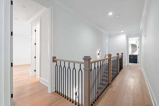 hall featuring ornamental molding, light wood-style flooring, an upstairs landing, and baseboards