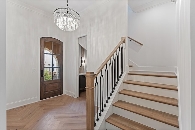 foyer featuring a notable chandelier, visible vents, baseboards, and crown molding