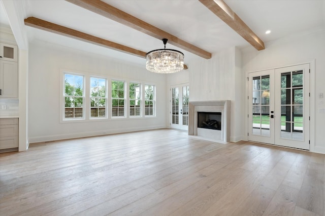 unfurnished living room featuring light wood finished floors, a notable chandelier, beam ceiling, and french doors