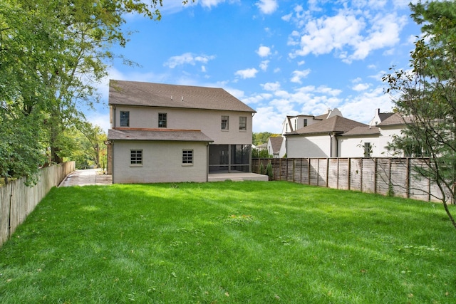 rear view of house with a sunroom, a fenced backyard, and a yard