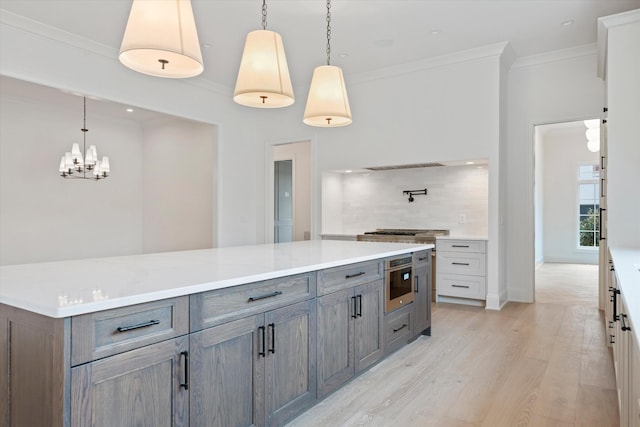 kitchen with light wood finished floors, gray cabinets, light countertops, backsplash, and ornamental molding