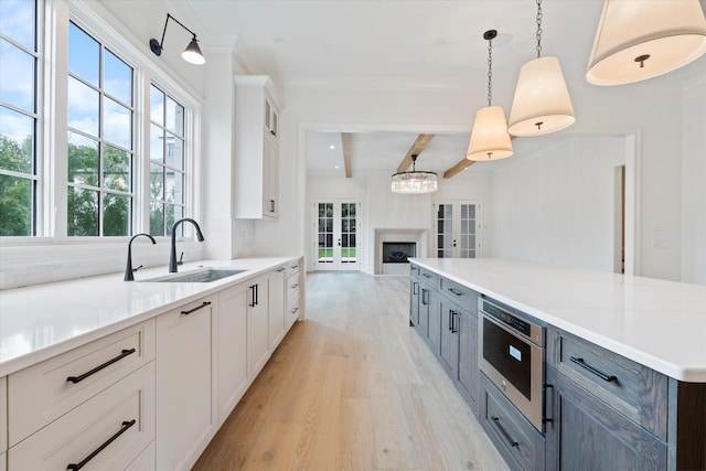 kitchen featuring a sink, white cabinetry, light countertops, french doors, and light wood-type flooring