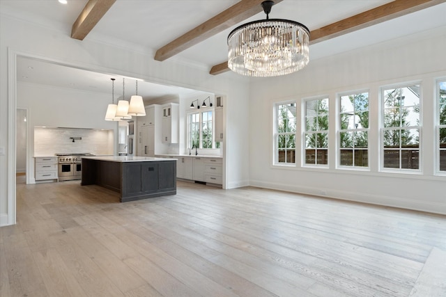 kitchen with range with two ovens, a notable chandelier, light wood-style floors, light countertops, and decorative backsplash