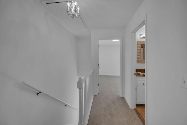 hallway with carpet floors, attic access, and an upstairs landing