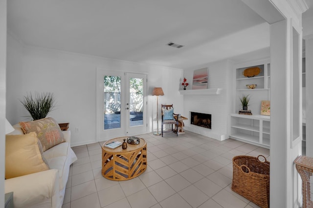 tiled living area featuring built in shelves, french doors, visible vents, and a fireplace with raised hearth
