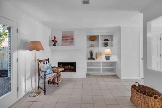 living area with visible vents, built in features, a brick fireplace, tile patterned floors, and crown molding