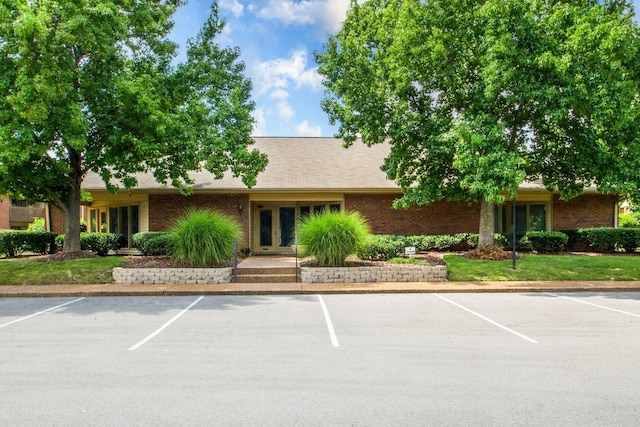 view of front of house featuring uncovered parking, french doors, and brick siding
