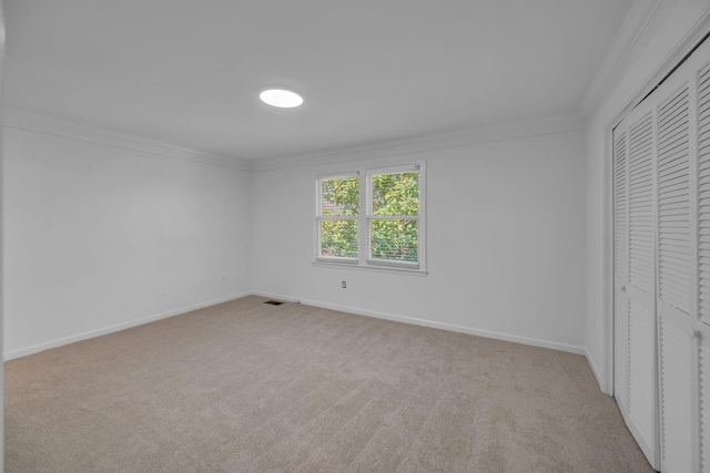 unfurnished bedroom featuring baseboards, ornamental molding, a closet, and light colored carpet