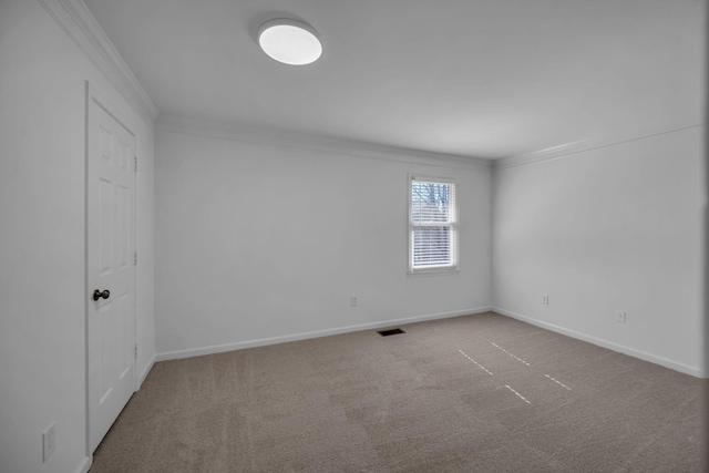 empty room with ornamental molding, carpet flooring, visible vents, and baseboards