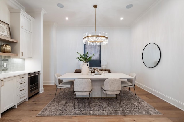 dining area featuring baseboards, wine cooler, ornamental molding, and wood finished floors