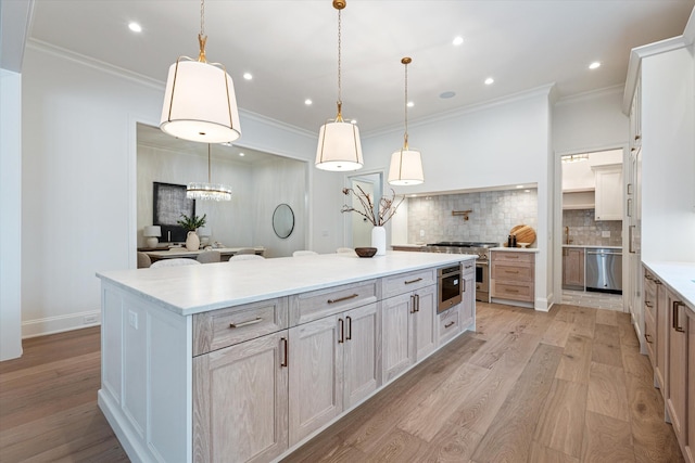 kitchen with stainless steel appliances, ornamental molding, a large island, decorative backsplash, and light wood finished floors