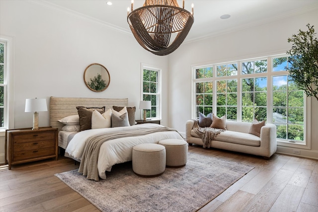 bedroom featuring ornamental molding, hardwood / wood-style floors, and an inviting chandelier