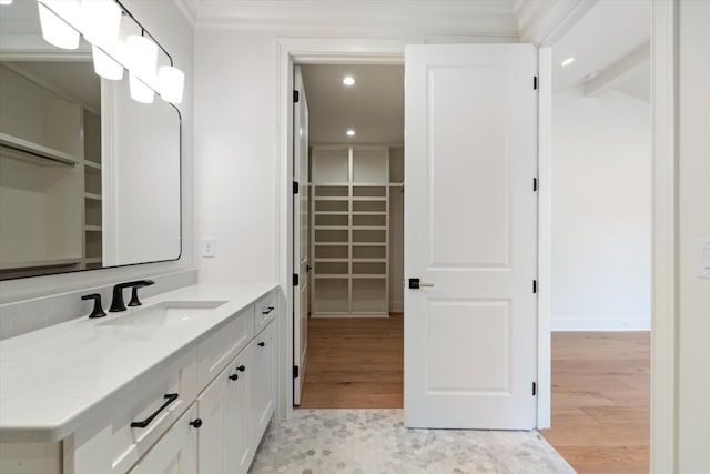 bathroom with a walk in closet, crown molding, recessed lighting, vanity, and wood finished floors