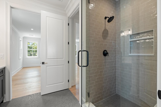 bathroom featuring crown molding, a shower stall, and wood finished floors